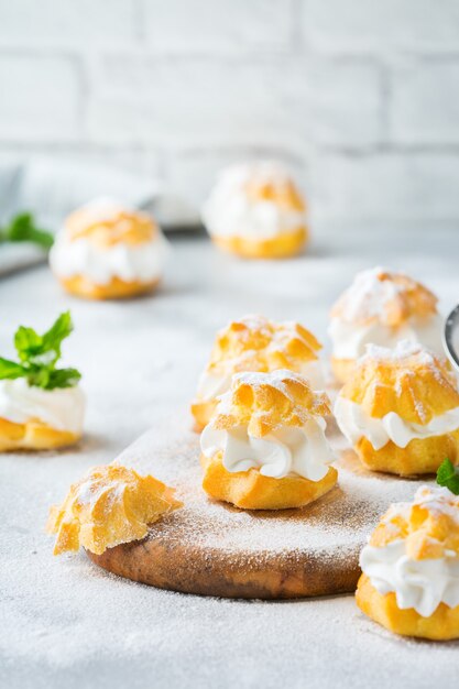 Comida e bebida, conceito de férias. Deliciosos profiteroles doces caseiros com creme em uma mesa de cozinha moderna
