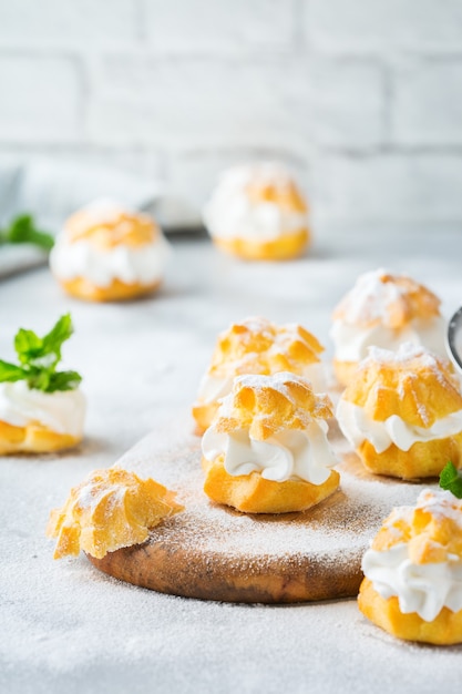 Comida e bebida, conceito de férias. deliciosos profiteroles doces caseiros com creme em uma moderna mesa de cozinha