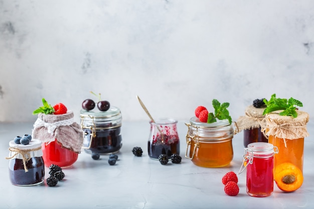 Comida e bebida, conceito de outono de verão de colheita. Variedade de frutas da estação e compotas de frutas em potes sobre uma mesa de madeira. Copie o fundo rústico do espaço