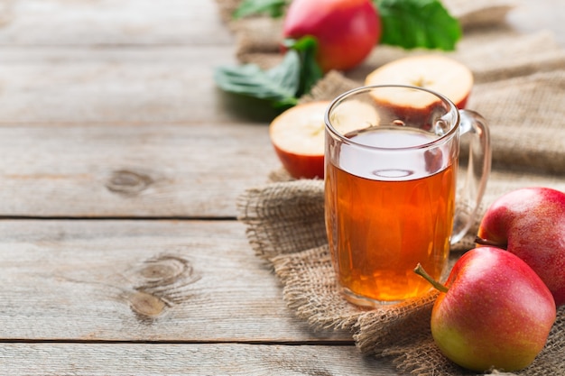 Comida e bebida, conceito de outono outono da colheita. Suco de maçã orgânico fresco em uma caneca com frutas maduras em fundo de madeira rústico. Copie o espaço