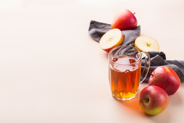 Comida e bebida, conceito de outono outono da colheita. Suco de maçã orgânico fresco em uma caneca com frutas maduras no fundo coral rosa da moda. Copie o espaço