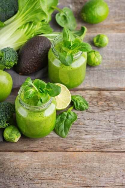 Comida e bebida, dieta e nutrição saudáveis, estilo de vida, conceito vegano, alcalino, vegetariano. smoothie verde com ingredientes orgânicos, vegetais em uma mesa de cozinha de madeira. copie o fundo do espaço