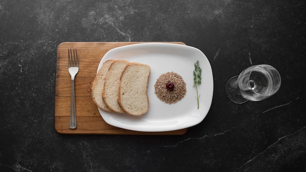 Comida em um prato branco de pé sobre uma placa de madeira com um garfo de metal em um fundo cinza escuro