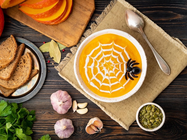 Comida engraçada para sopa de purê de abóbora de halloween teia de aranha escura velha mesa de madeira vista superior