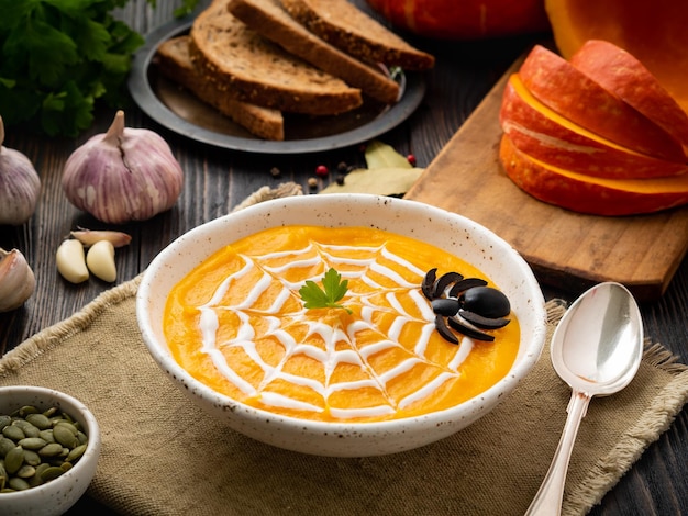 Comida engraçada para sopa de purê de abóbora de halloween teia de aranha escura vista lateral da mesa de madeira velha