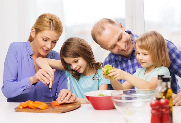 Comida, família, crianças, felicidade e conceito de pessoas - família feliz com dois filhos fazendo jantar em casa