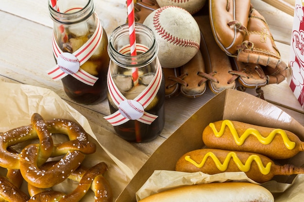 Comida de fiesta de béisbol con pelotas y guante en una mesa de madera.