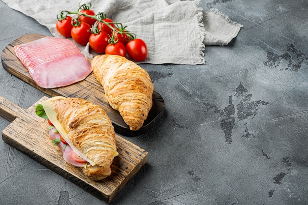 Comida francesa no café da manhã. conjunto de sanduíche de croissant assado com folhas de presunto e queijo, em fundo de pedra cinza, com espaço de cópia para o texto