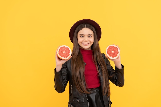 Comida fresca cruda orgánica natural infancia saludable niña feliz en cuero sostener pomelo elegante niño adolescente vitamina dieta diversión y salud niño sostener pomelo cortado cuidado de la piel frutas de temporada de otoño