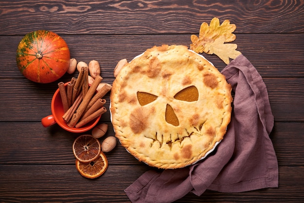 Foto comida de halloween. pastel de calabaza casero o tarta con cara de miedo para halloween en una mesa de madera. copie el espacio. concepto de comida de halloween.