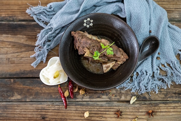 La comida hecha de carne está en el cuenco sobre el mantel de la mesa de madera.