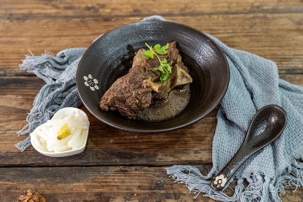 La comida hecha de carne está en el cuenco sobre el mantel de la mesa de madera.