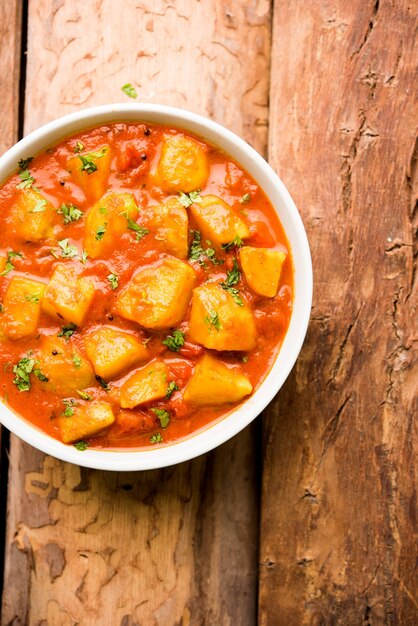 Comida india - Aloo curry masala. Patata cocida con especias y hierbas en un curry de tomate. servido en un cuenco sobre fondo de mal humor. enfoque selectivo