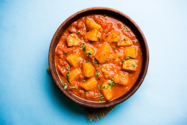 Comida india - Aloo curry masala. Patata cocida con especias y hierbas en un curry de tomate. servido en un cuenco sobre fondo de mal humor. enfoque selectivo