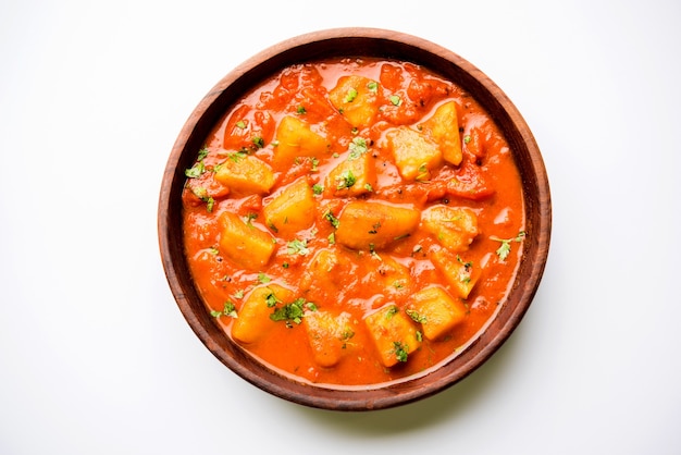 Comida india - Aloo curry masala. Patata cocida con especias y hierbas en un curry de tomate. servido en un cuenco sobre fondo de mal humor. enfoque selectivo