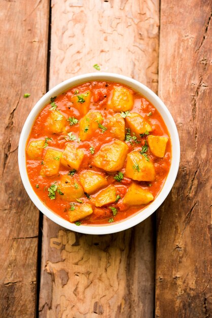 Comida indiana - Aloo curry masala. Batata cozida com especiarias e ervas em um curry de tomate. servido em uma tigela sobre fundo mal-humorado. foco seletivo