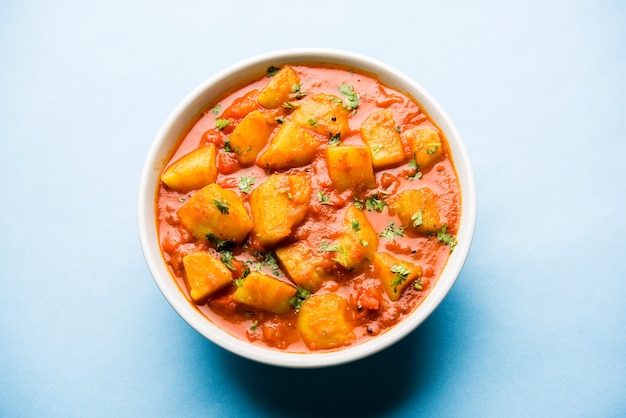 Comida indiana - Aloo curry masala. Batata cozida com especiarias e ervas em um curry de tomate. servido em uma tigela sobre fundo mal-humorado. foco seletivo