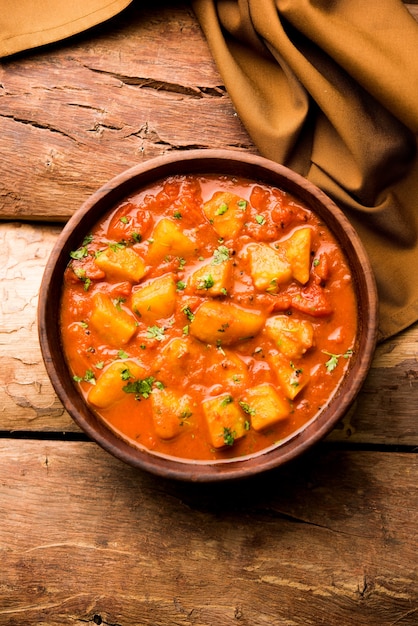 Comida indiana - Aloo curry masala. Batata cozida com especiarias e ervas em um curry de tomate. servido em uma tigela sobre fundo mal-humorado. foco seletivo