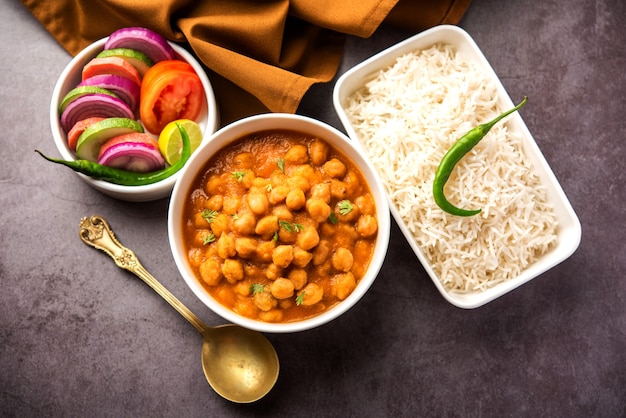 Comida indiana chole chawal ou curry picante de grão de bico com arroz puro servido com salada verde. foco seletivo