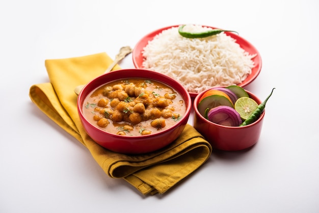 Comida indiana chole chawal ou curry picante de grão de bico com arroz puro servido com salada verde