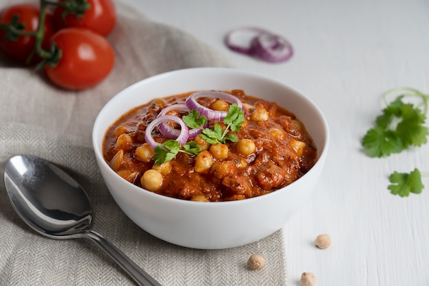 Comida indiana vegan Chole masala feita de grão de bico e tomate em uma tigela com uma colher em tecido