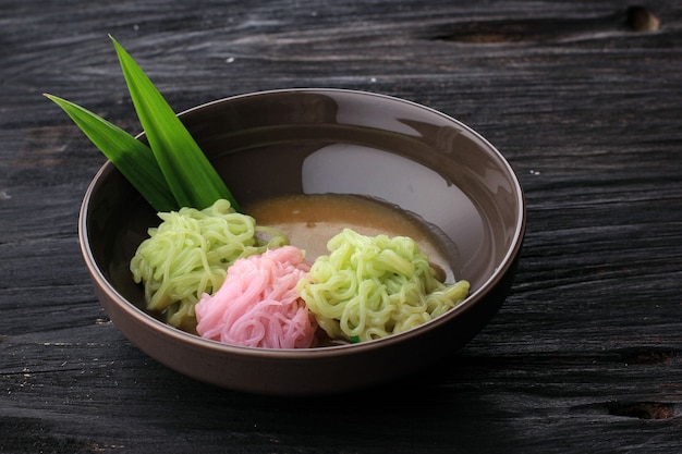 Foto comida indonésia: putu mayang ou petulo, lanche tradicional indonésio javanês feito de fios de farinha de arroz enrolados em uma bola com corante alimentício, servido com leite de coco e xarope de açúcar de palma.