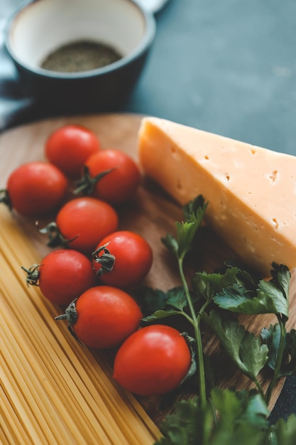 Comida italiana para cocinar, tomates, albahaca, pasta y queso sobre fondo de piedra, vista superior, espacio de copia