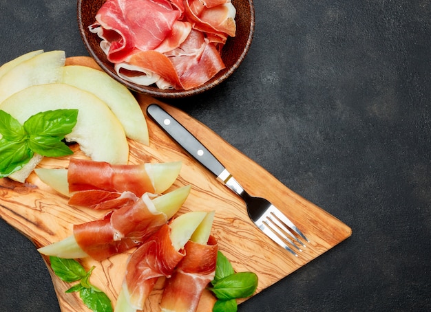 Comida italiana com melão e presunto na tábua de madeira