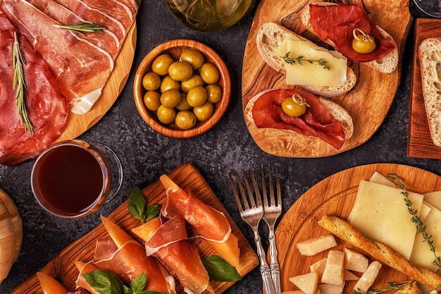 Foto comida italiana com presunto, queijo, azeitonas, pão, vinho.