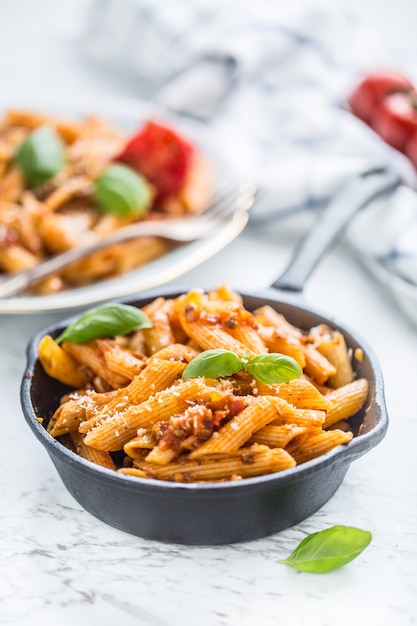 Comida italiana e macarrão penne com molho à bolonhesa na panela.