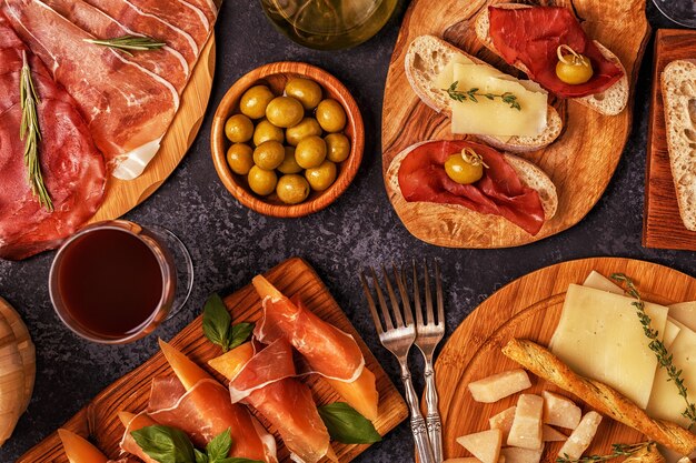 Foto comida italiana con jamón, queso, aceitunas, pan, vino.