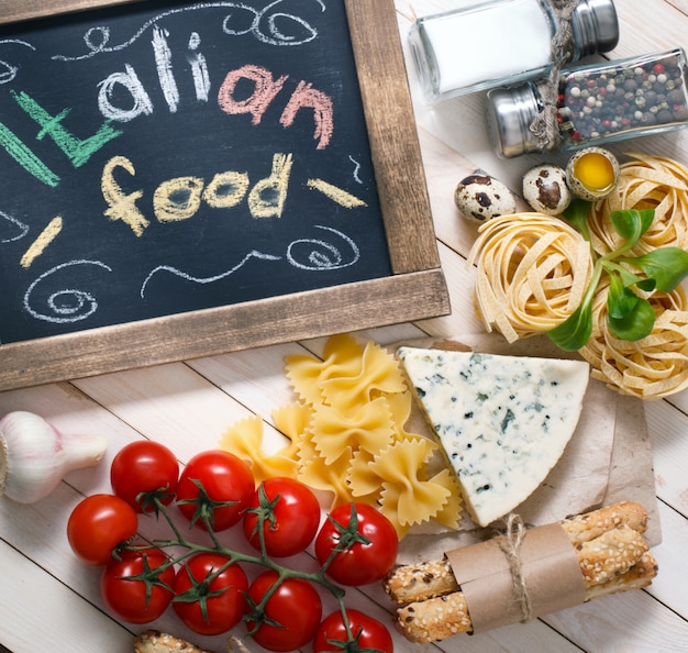 Comida italiana sobre fondo de madera vintage con pizarra