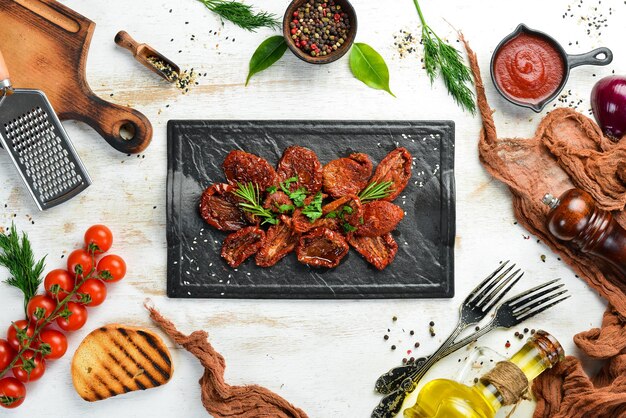 Comida italiana Tomates secos ao sol com ervas frescas e especiarias em uma placa de pedra preta Vista superior