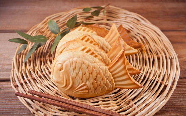 La comida japonesa de la calle de Taiyaki en forma de pescado rellenó la galleta en la tabla de madera.