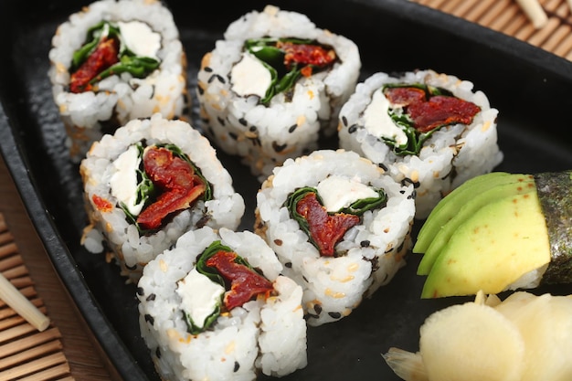 Comida japonesa y cebollas crujientes servidas en un restaurante en un bote negro sobre una mesa de madera