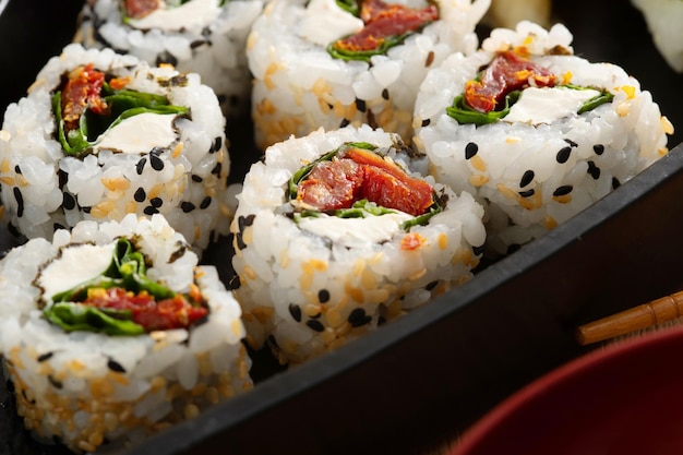 Comida japonesa e cebolas crocantes servidas no restaurante em barco preto na mesa de madeira