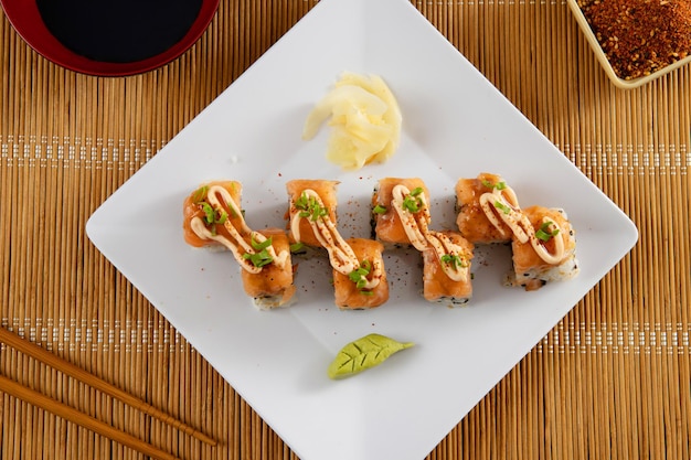 Comida japonesa e cebolas crocantes servidas no restaurante na chapa branca na mesa de madeira