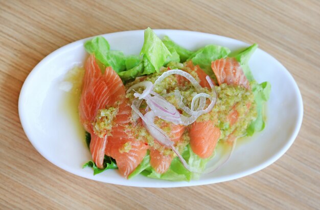 Comida japonesa, salada de salmão picante na mesa de madeira.