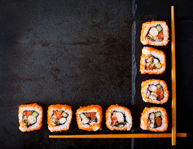 Comida japonesa tradicional - sushi, pãezinhos e pauzinhos para sushi em um fundo escuro. vista do topo