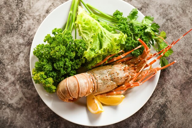 comida de langosta espinosa en el plato langosta fresca o langosta de roca mariscos con hierbas y especias limón cilantro perejil lechuga ensalada langosta para cocinar alimentos