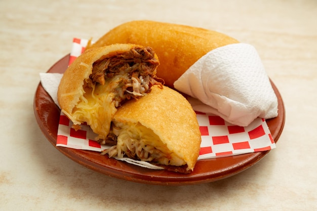 Foto comida latinoamericana empanada venezolana peluda, carne desmenuzada con queso amarillo