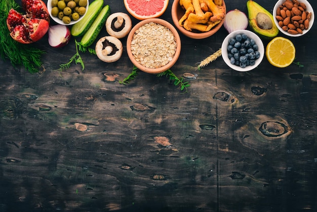 Comida legumes frutas nozes e bagas vitaminas em uma velha mesa de madeira vista superior espaço livre para texto