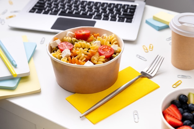 Comida para llevar cajas en mesa blanca con portátil.