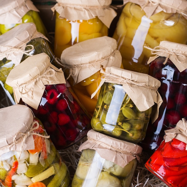 Comida local em conserva e fermentada. Variedade de potes caseiros com uma variedade de vegetais em conserva e marinados, compota de frutas em uma mesa de madeira. Limpeza, economia doméstica, preservação da colheita