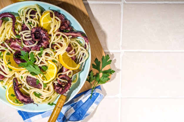 Comida mediterránea, pasta de pulpo casera con limón y hierbas, en el espacio de copia de vista superior de fondo soleado de verano de baldosas