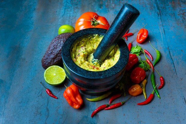 Comida mexicana guacamole en mortero con verduras y fondo texturizado