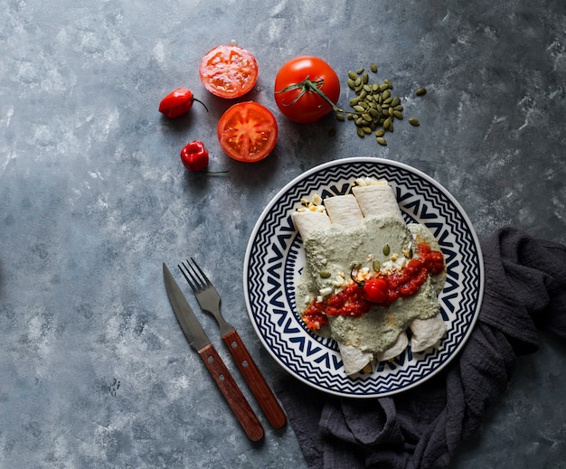 Comida mexicana: plato tradicional de Papadzules de la península de Yucatán: tortillas de maíz bañadas en una salsa de semillas de calabaza rellenas de huevos duros, adornadas con una salsa de tomate y pimiento cocido