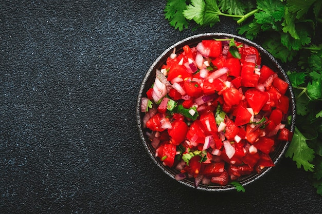 Comida mexicana Salsa picante con tomates, chiles, cebolla, ajo y cilantro, vista superior de fondo de mesa negra