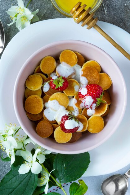 Comida de moda: cereal para panqueques. Montón de mini tortitas de cereales con fresas y yogur en boul light. Vista superior o endecha plana.