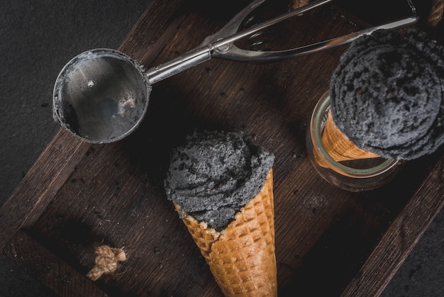 Comida de moda. Helado negro con sésamo negro, en conos de helado en porciones tradicionales